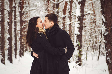 A guy and a girl in warm clothes and scarves on a walk in the snowy forest and in the fieldの写真素材