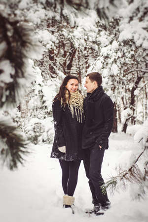 A guy and a girl in warm clothes and scarves on a walk in the snowy forest and in the fieldの写真素材