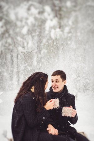 A guy and a girl in warm clothes and scarves on a walk in the snowy forest and in the fieldの写真素材