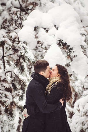 A guy and a girl in warm clothes and scarves on a walk in the snowy forest and in the fieldの写真素材