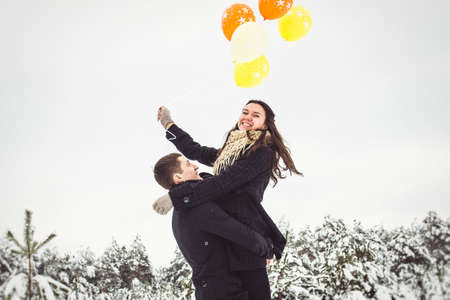 A guy and a girl in warm clothes and scarves on a walk in the snowy forest and in the fieldの写真素材