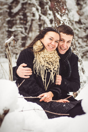 A guy and a girl in warm clothes and scarves on a walk in the snowy forest and in the fieldの写真素材