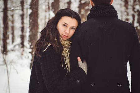 A guy and a girl in warm clothes and scarves on a walk in the snowy forest and in the fieldの写真素材