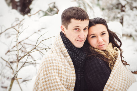 A guy and a girl in warm clothes and scarves on a walk in the snowy forest and in the fieldの写真素材