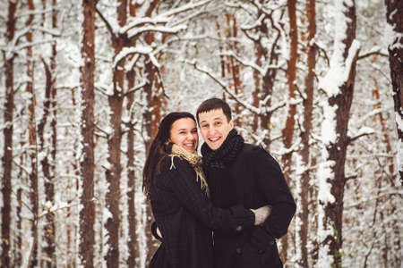 A guy and a girl in warm clothes and scarves on a walk in the snowy forest and in the fieldの写真素材