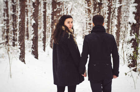 A guy and a girl in warm clothes and scarves on a walk in the snowy forest and in the fieldの写真素材
