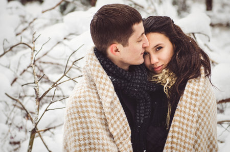 A guy and a girl in warm clothes and scarves on a walk in the snowy forest and in the fieldの写真素材