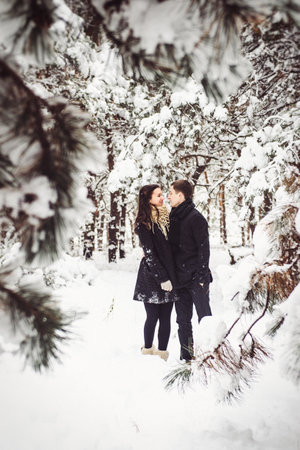A guy and a girl in warm clothes and scarves on a walk in the snowy forest and in the fieldの写真素材