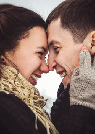 A guy and a girl in warm clothes and scarves on a walk in the snowy forest and in the fieldの写真素材