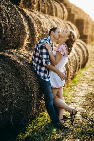 a guy with a girl on a summer walk in the field near round haystacksの写真素材