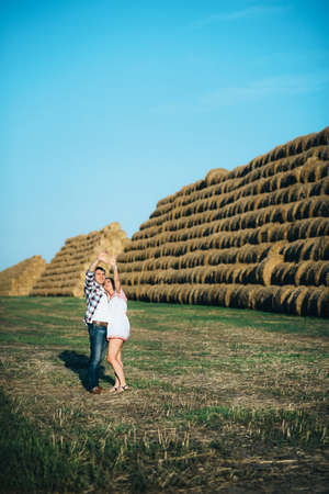 a guy with a girl on a summer walk in the field near round haystacksの写真素材