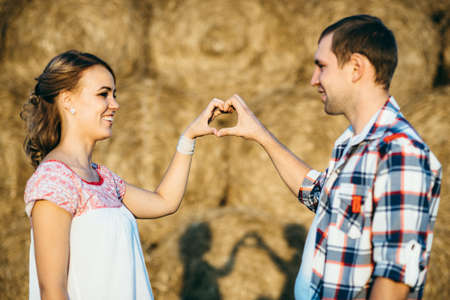 a guy with a girl on a summer walk in the field near round haystacksの写真素材