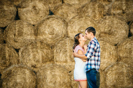 a guy with a girl on a summer walk in the field near round haystacksの写真素材