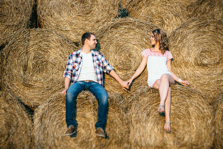 a guy with a girl on a summer walk in the field near round haystacksの写真素材