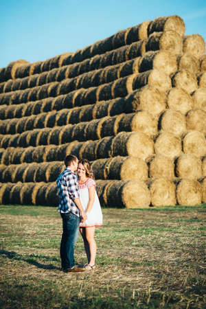 a guy with a girl on a summer walk in the field near round haystacksの写真素材