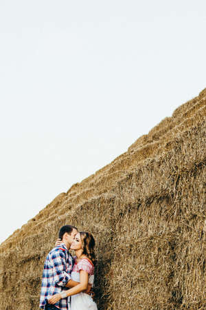 a guy with a girl on a summer walk in the field near round haystacksの写真素材