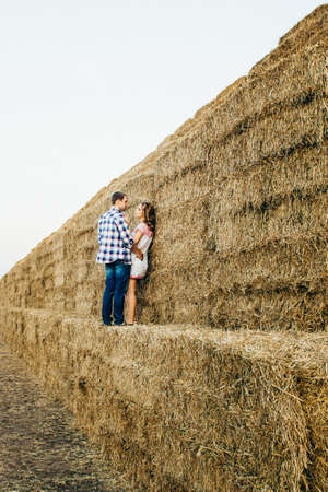 a guy with a girl on a summer walk in the field near round haystacksの写真素材