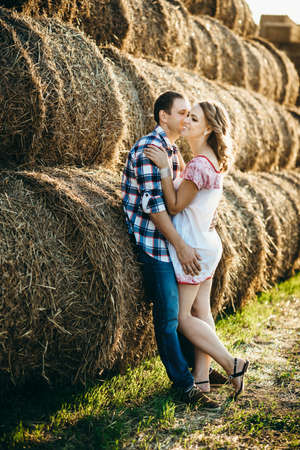 a guy with a girl on a summer walk in the field near round haystacksの写真素材
