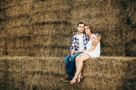 a guy with a girl on a summer walk in the field near round haystacksの写真素材
