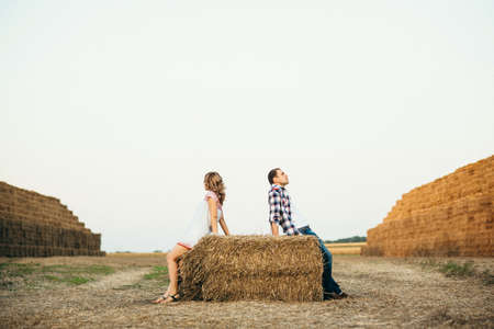 a guy with a girl on a summer walk in the field near round haystacksの写真素材