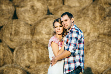 a guy with a girl on a summer walk in the field near round haystacksの写真素材