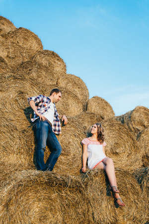 a guy with a girl on a summer walk in the field near round haystacksの写真素材