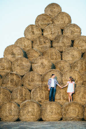 a guy with a girl on a summer walk in the field near round haystacksの写真素材