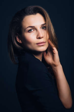girl brunette beauty model in a black jacket on a dark blue backgroundの写真素材