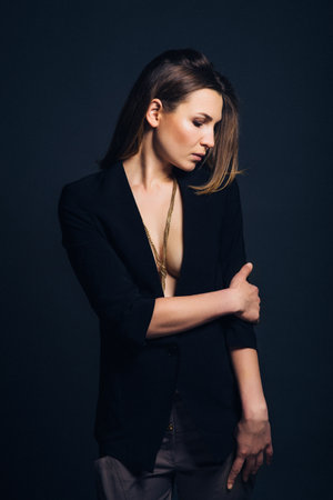 girl brunette beauty model in a black jacket on a dark blue backgroundの写真素材
