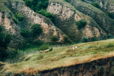 a guy with a girl in light clothes on the background of a green canyon of erosion of the earthの写真素材