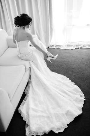 bride in a white dress with a bouquet in a hotel roomの写真素材
