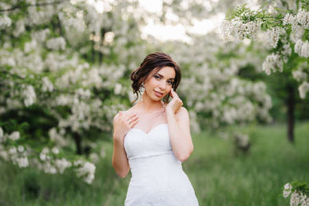 bride in a white dress with a large spring bouquet in a green forestの写真素材