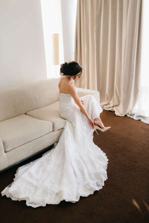 bride in a white dress with a bouquet in a hotel roomの写真素材