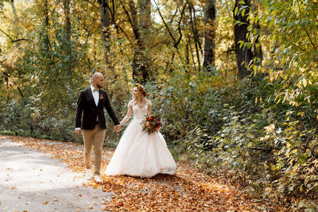 walk of the bride and groom through the autumn forest in Octoberの写真素材