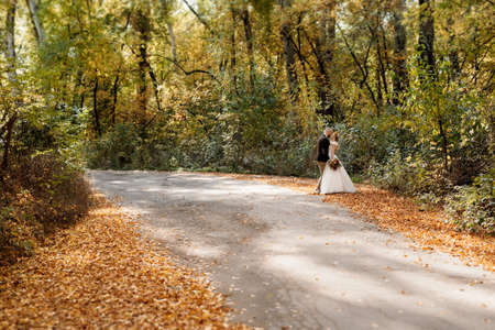 walk of the bride and groom through the autumn forest in Octoberの写真素材