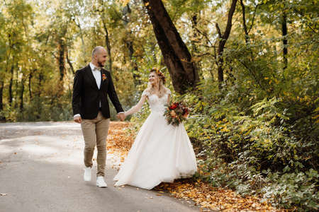 walk of the bride and groom through the autumn forest in Octoberの写真素材