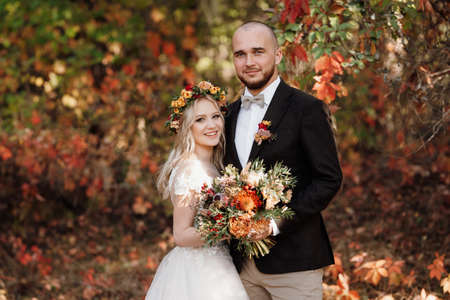 walk of the bride and groom through the autumn forest in Octoberの写真素材