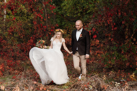 walk of the bride and groom through the autumn forest in Octoberの写真素材
