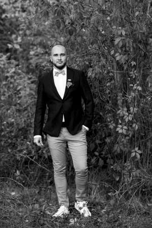 bald bearded guy in a brown jacket on a background of red wild grapesの写真素材