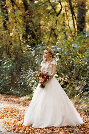 blonde girl in a wedding dress in the autumn forestの写真素材