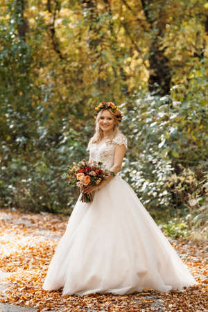 blonde girl in a wedding dress in the autumn forestの写真素材
