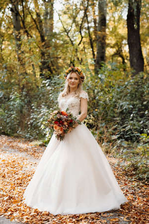 blonde girl in a wedding dress in the autumn forestの写真素材