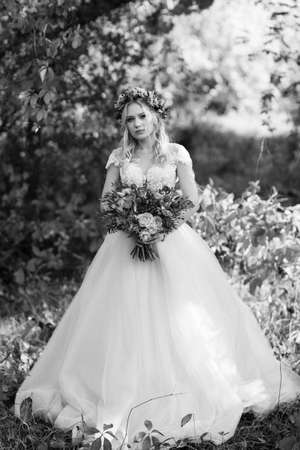 blonde girl in a wedding dress in the autumn forest against the background of wild red grapesの写真素材
