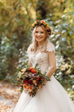 blonde girl in a wedding dress in the autumn forestの写真素材