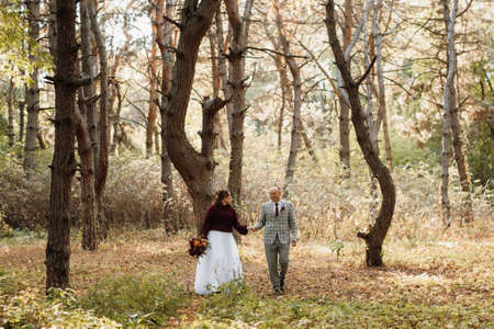 walk of the bride and groom through the autumn forest in Octoberの写真素材