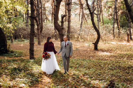 walk of the bride and groom through the autumn forest in Octoberの写真素材