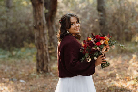 girl in a wedding dress in the autumn forest against the background of wild treesの写真素材