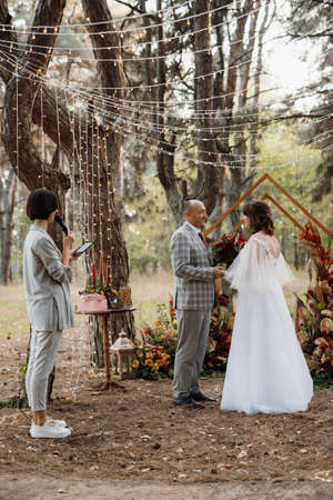 man and woman got engaged in autumn forest at wedding decorated ceremonyの写真素材