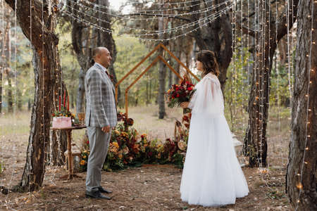 man and woman got engaged in autumn forest at wedding decorated ceremonyの写真素材