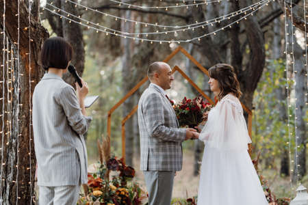 man and woman got engaged in autumn forest at wedding decorated ceremonyの写真素材